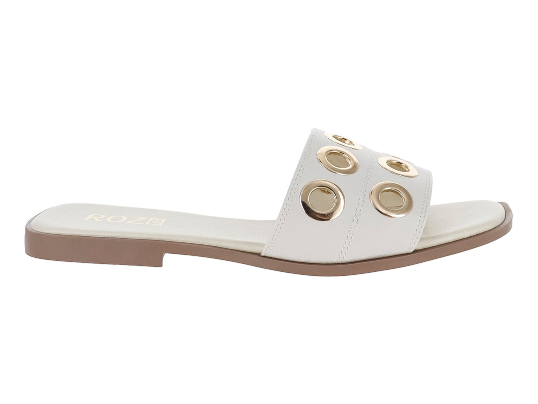 Sandalia plana color beige para mujer con detalles de orificios metálicos dorados en la banda superior.