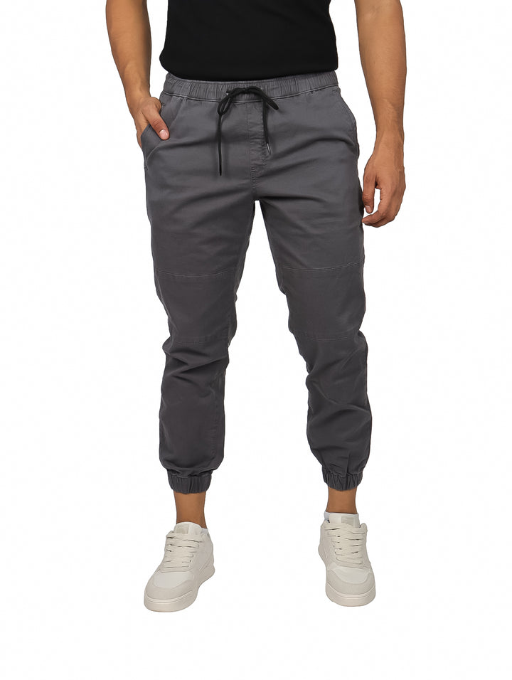 Hombre vistiendo pantalones jogger color gris oxford con cintura elástica y calzado blanco.
