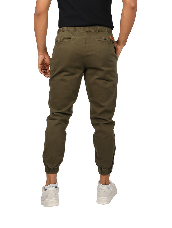 Hombre vistiendo pantalones jogger color olivo con cintura elástica y cordones negros.