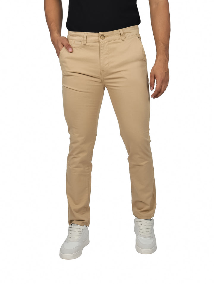 Hombre vistiendo un pantalón chino slim en color camel con calzado blanco sobre fondo blanco.