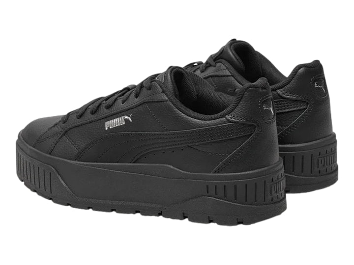 Tenis PUMA color negro con suela de plataforma gruesa y logotipo plateado en el costado.
