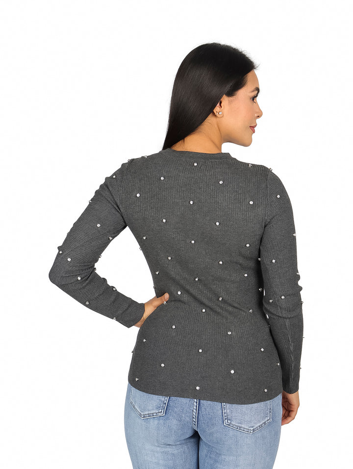 Mujer vistiendo blusa gris de manga larga con pequeños detalles de piedras blancas distribuidas en toda la prenda.