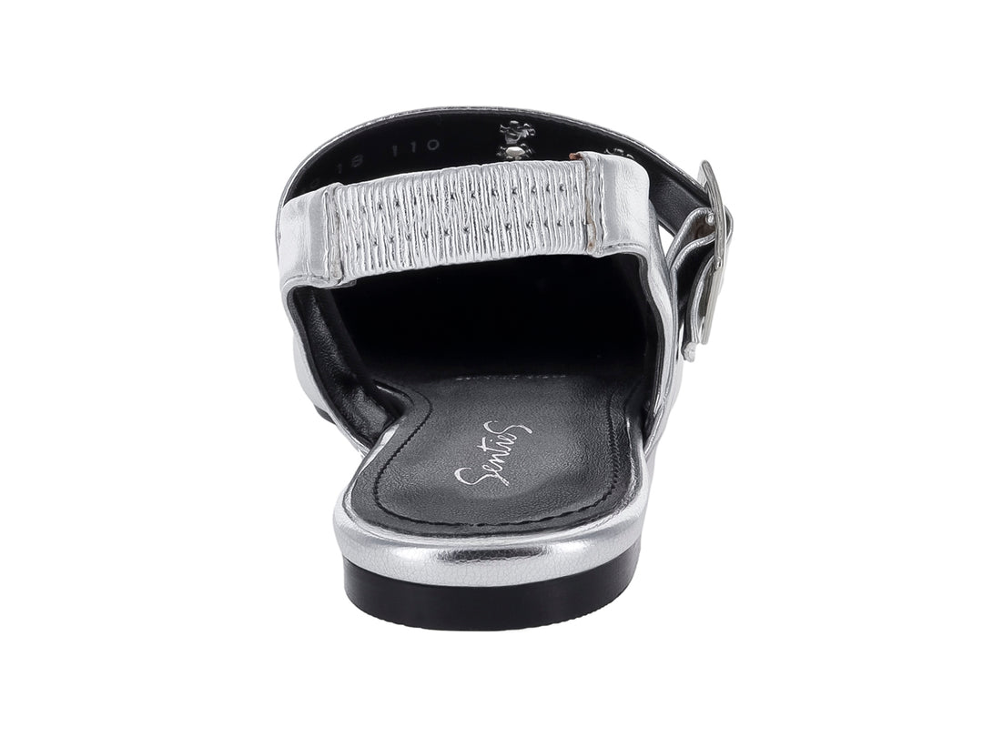 Zapato plano color plata con punta aguda, hebilla decorativa y correa posterior.