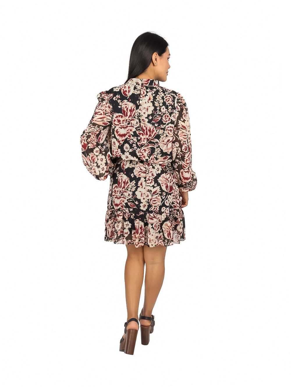 Mujer vistiendo un vestido corto negro con estampado floral en tonos rojo y crema y mangas largas.