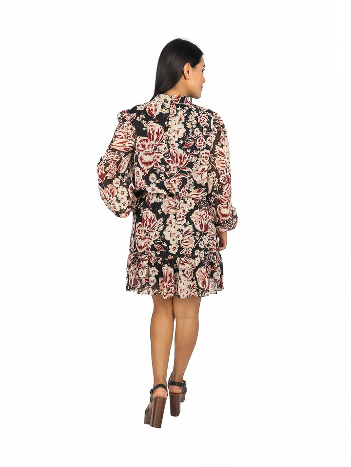Mujer vistiendo un vestido corto negro con estampado floral en tonos rojo y crema y mangas largas.
