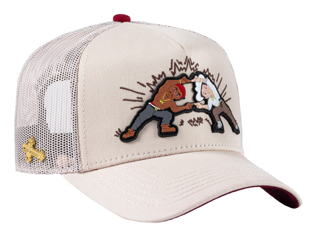 Gorra trucker beige con parche gráfico frontal y malla trasera.