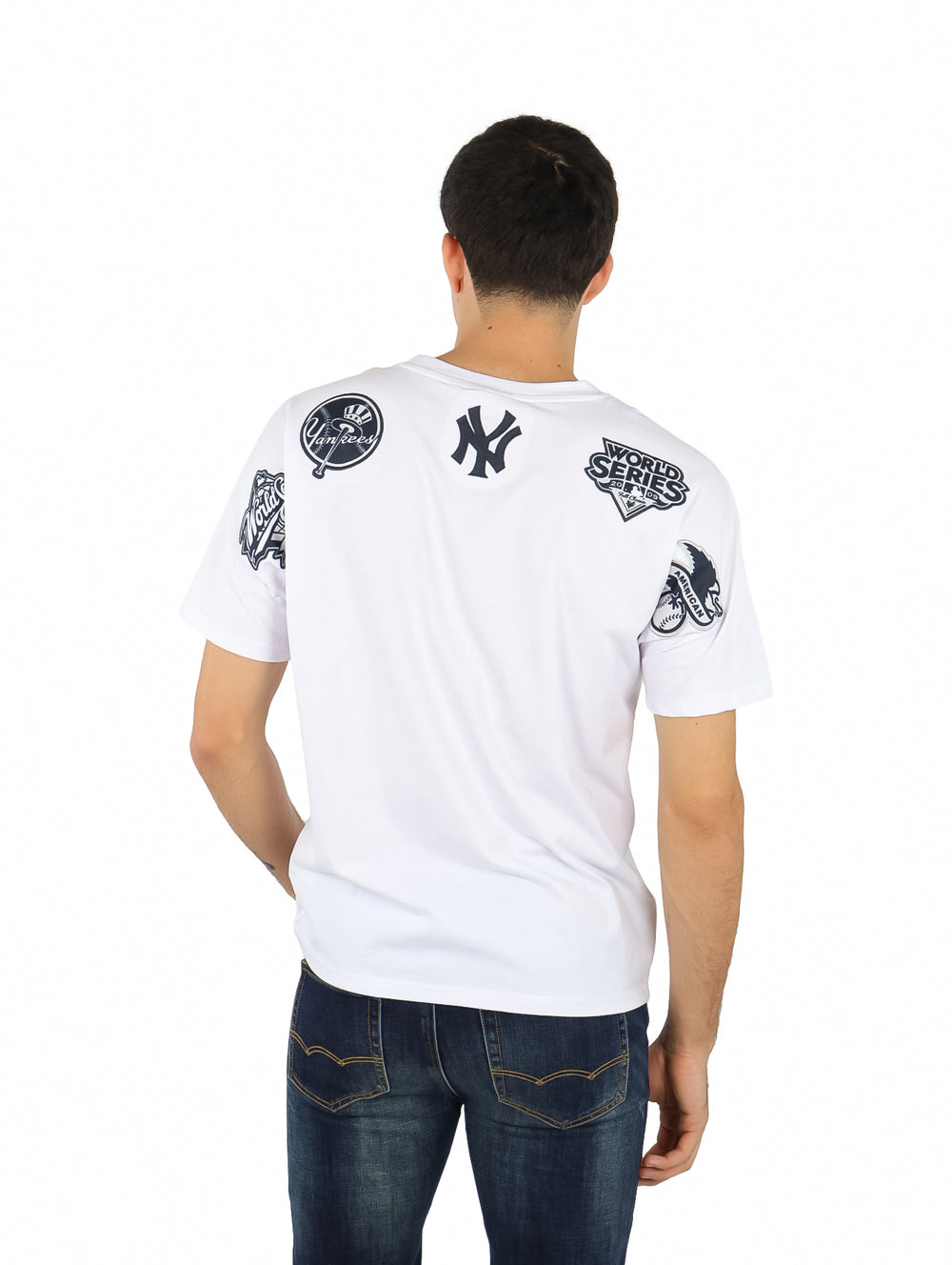 Hombre vistiendo una playera blanca de manga corta con el logo de los New York Yankees en el pecho.