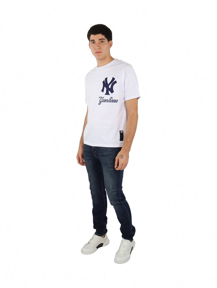 Hombre vistiendo una playera blanca de manga corta con el logo de los New York Yankees en el pecho.