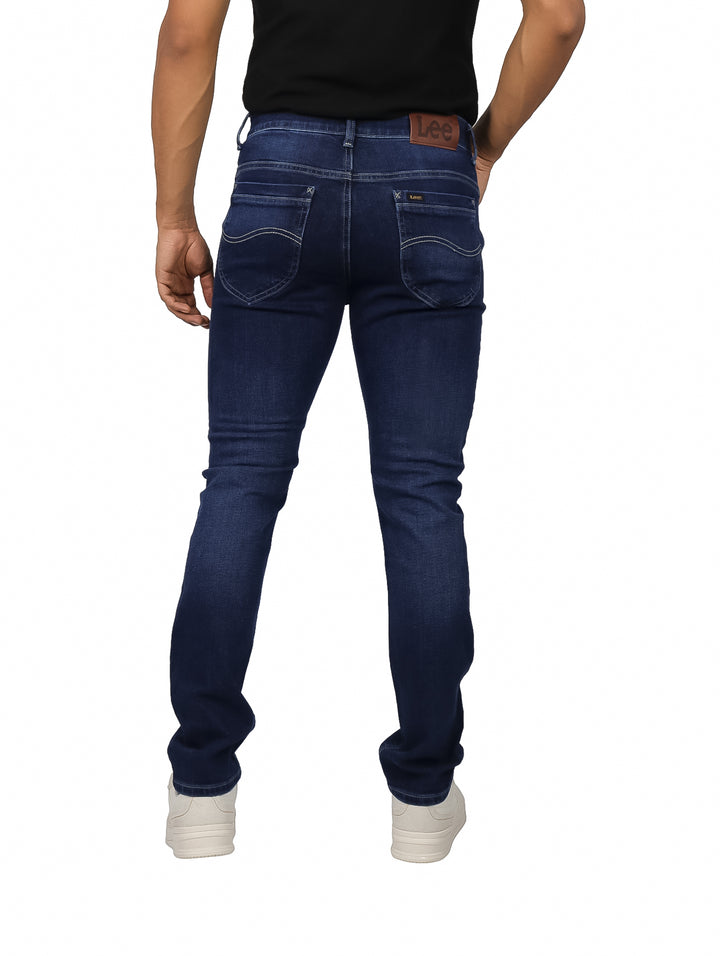 Hombre vistiendo pantalones LEE slim fit en color azul índigo.