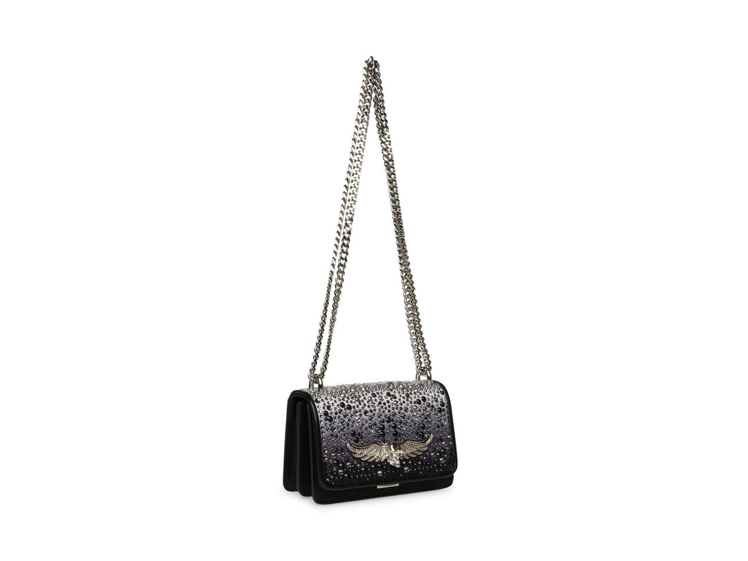 Bolso negro de Steve Madden con cadena plateada, detalles de pedrería brillante y un adorno metálico en forma de ave.