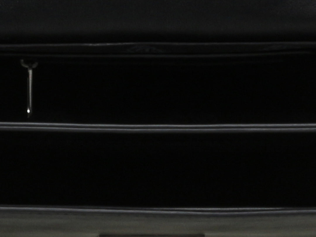 Bolso negro de Steve Madden con cadena plateada, detalles de pedrería brillante y un adorno metálico en forma de ave.
