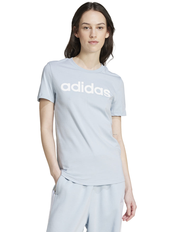 Mujer vistiendo playera ajustada y pantalones de color celeste claro con logo de Adidas en el pecho.