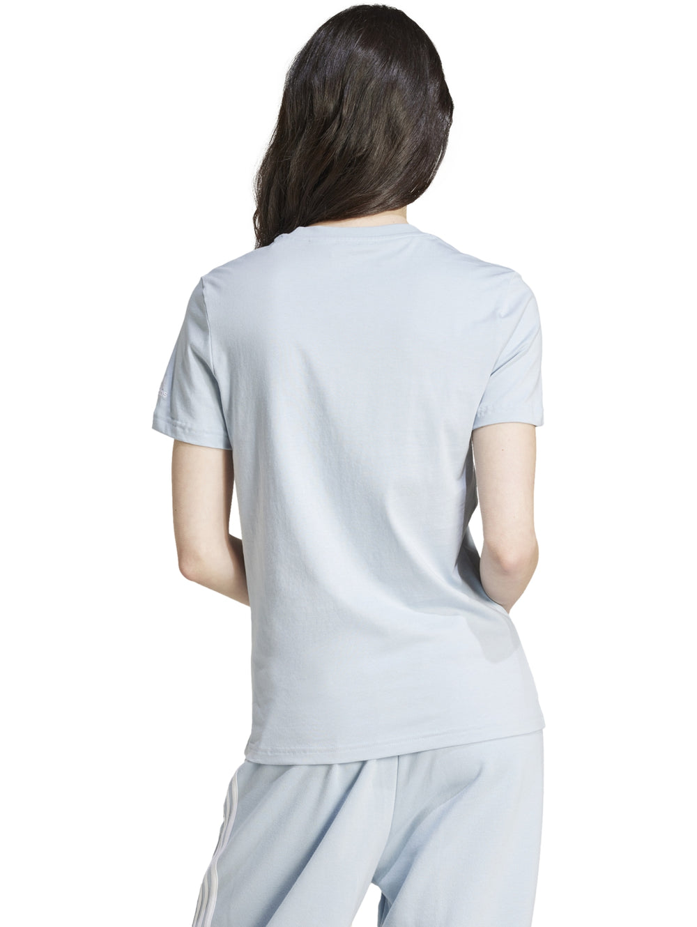 Mujer vistiendo playera ajustada y pantalones de color celeste claro con logo de Adidas en el pecho.