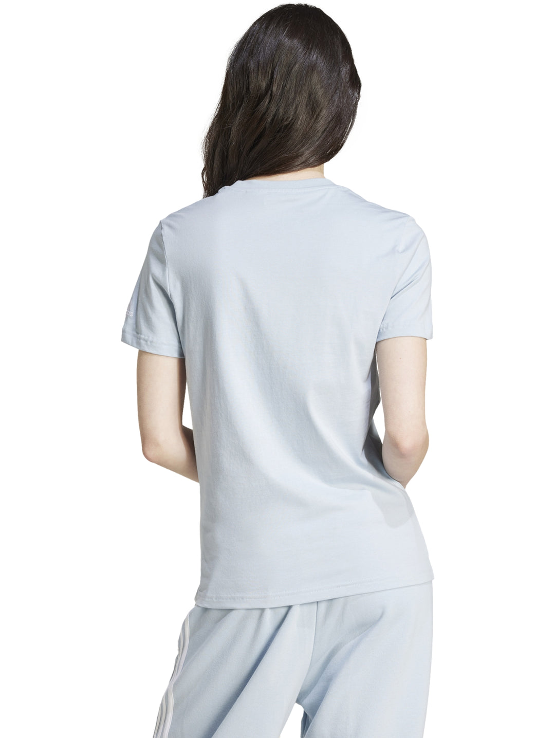 Mujer vistiendo playera ajustada y pantalones de color celeste claro con logo de Adidas en el pecho.