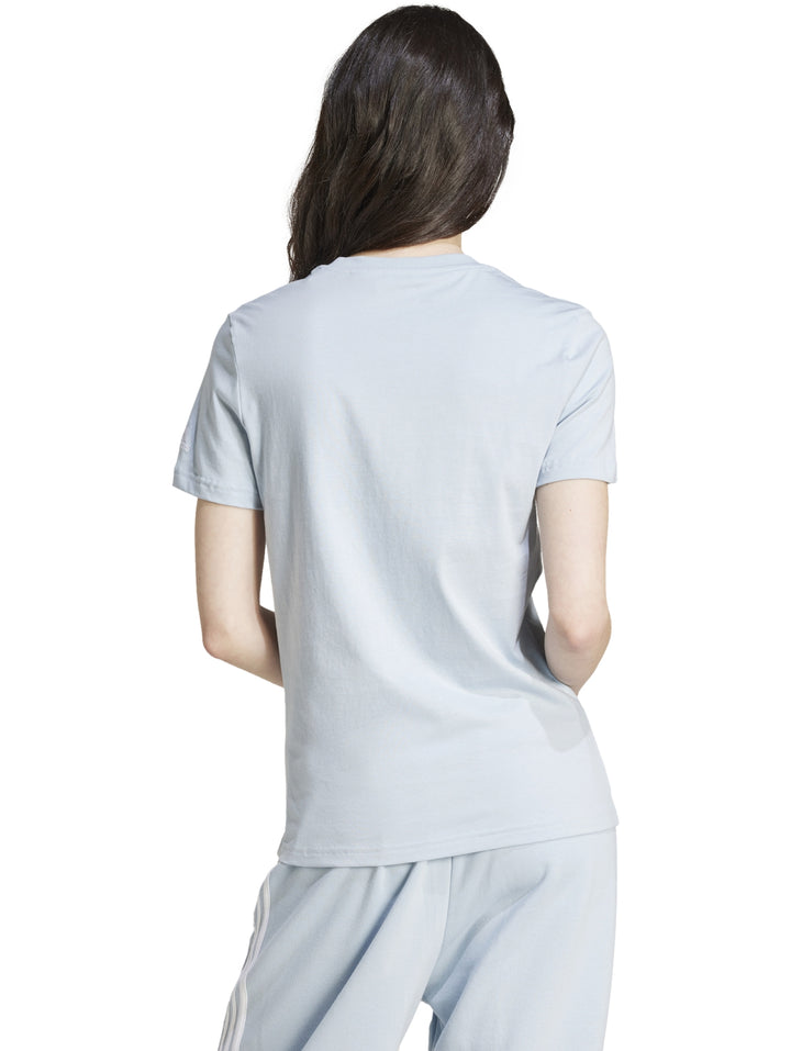 Mujer vistiendo playera ajustada y pantalones de color celeste claro con logo de Adidas en el pecho.