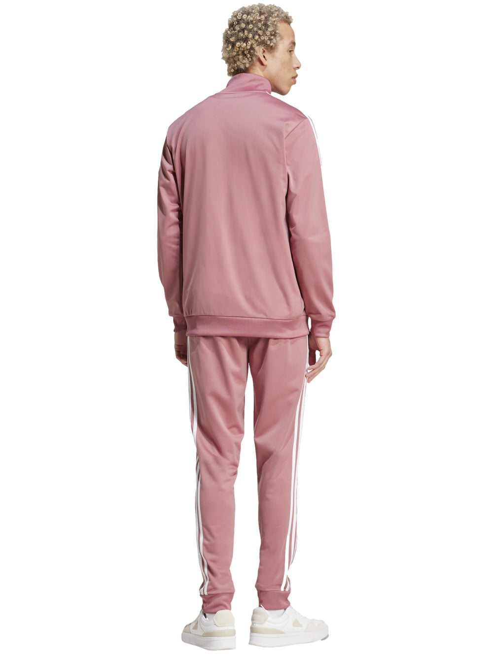 Hombre vistiendo conjunto deportivo Adidas de color rosa con tres franjas blancas laterales.