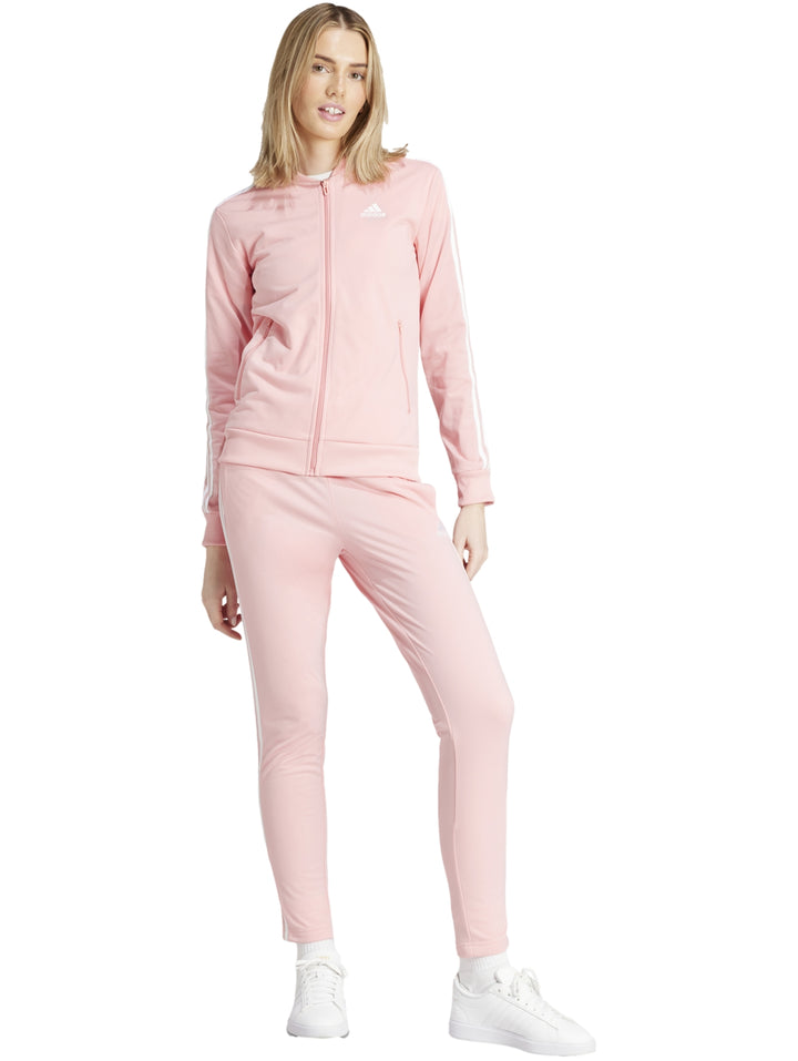 Conjunto deportivo Adidas color rosa claro con tres franjas blancas laterales, incluye chaqueta y pantalón para mujer.