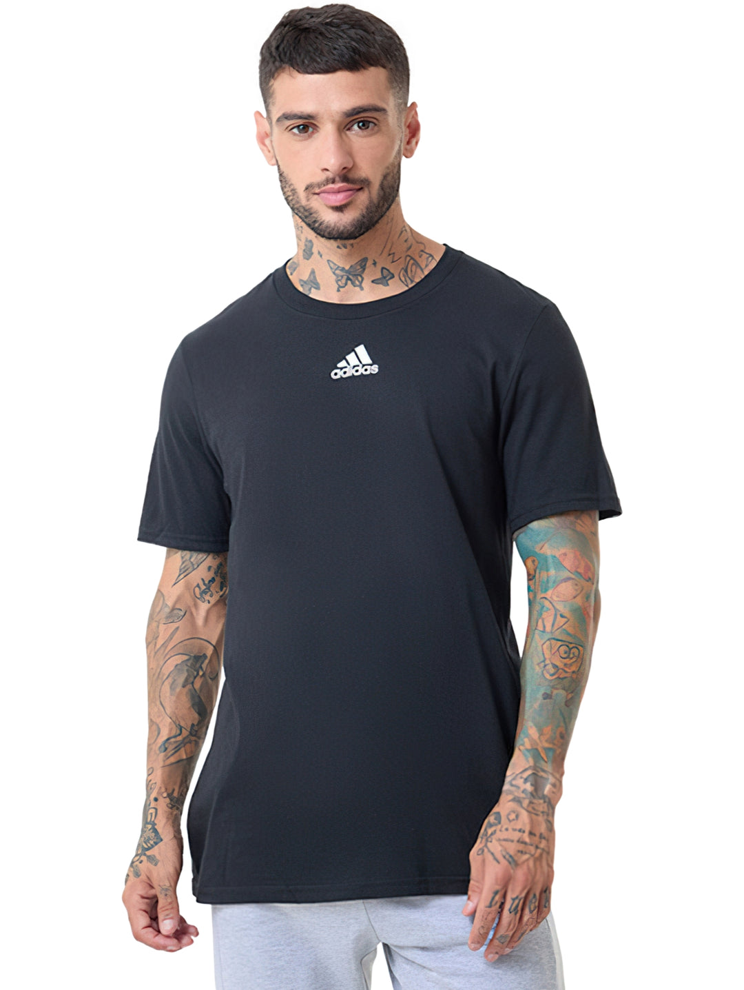 Hombre vistiendo camiseta negra de manga corta con logo pequeño de Adidas en el pecho.