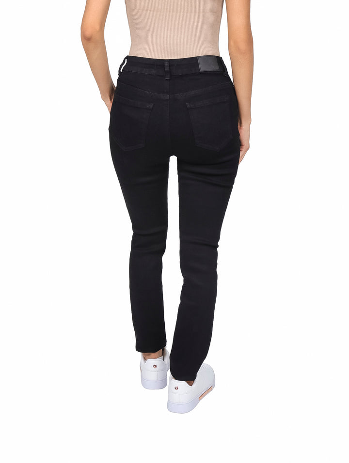 Mujer vistiendo jeans skinny de color negro con cintura alta y tenis blancos.