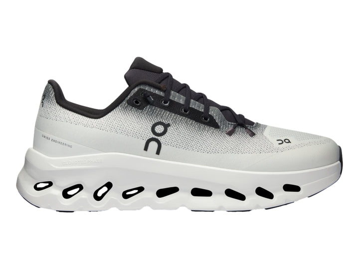 Tenis deportivos On Cloud en color marfil con detalles en negro y suela blanca con diseño de nubes.