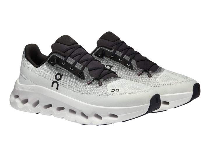 Tenis deportivos On Cloud en color marfil con detalles en negro y suela blanca con diseño de nubes.