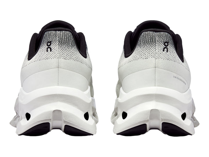 Tenis deportivos On Cloud en color marfil con detalles en negro y suela blanca con diseño de nubes.