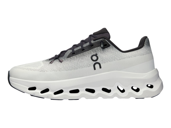 Tenis deportivos On Cloud en color marfil con detalles en negro y suela blanca con diseño de nubes.