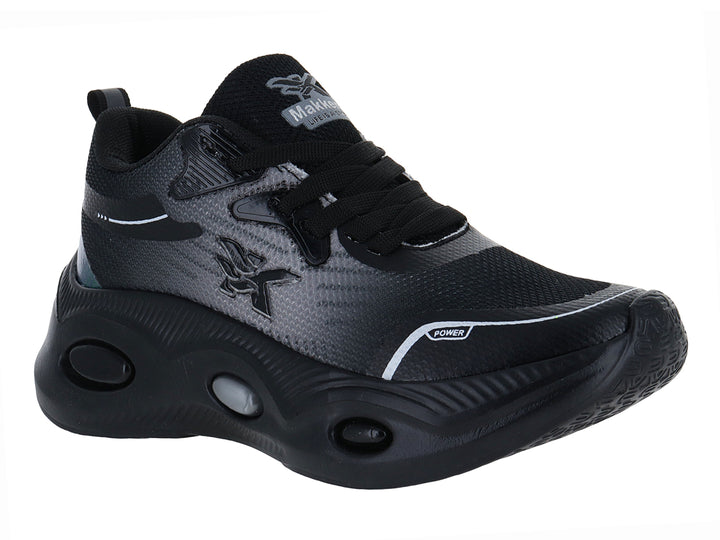 Tenis deportivos infantiles de color negro con detalles en verde y blanco y suela gruesa.