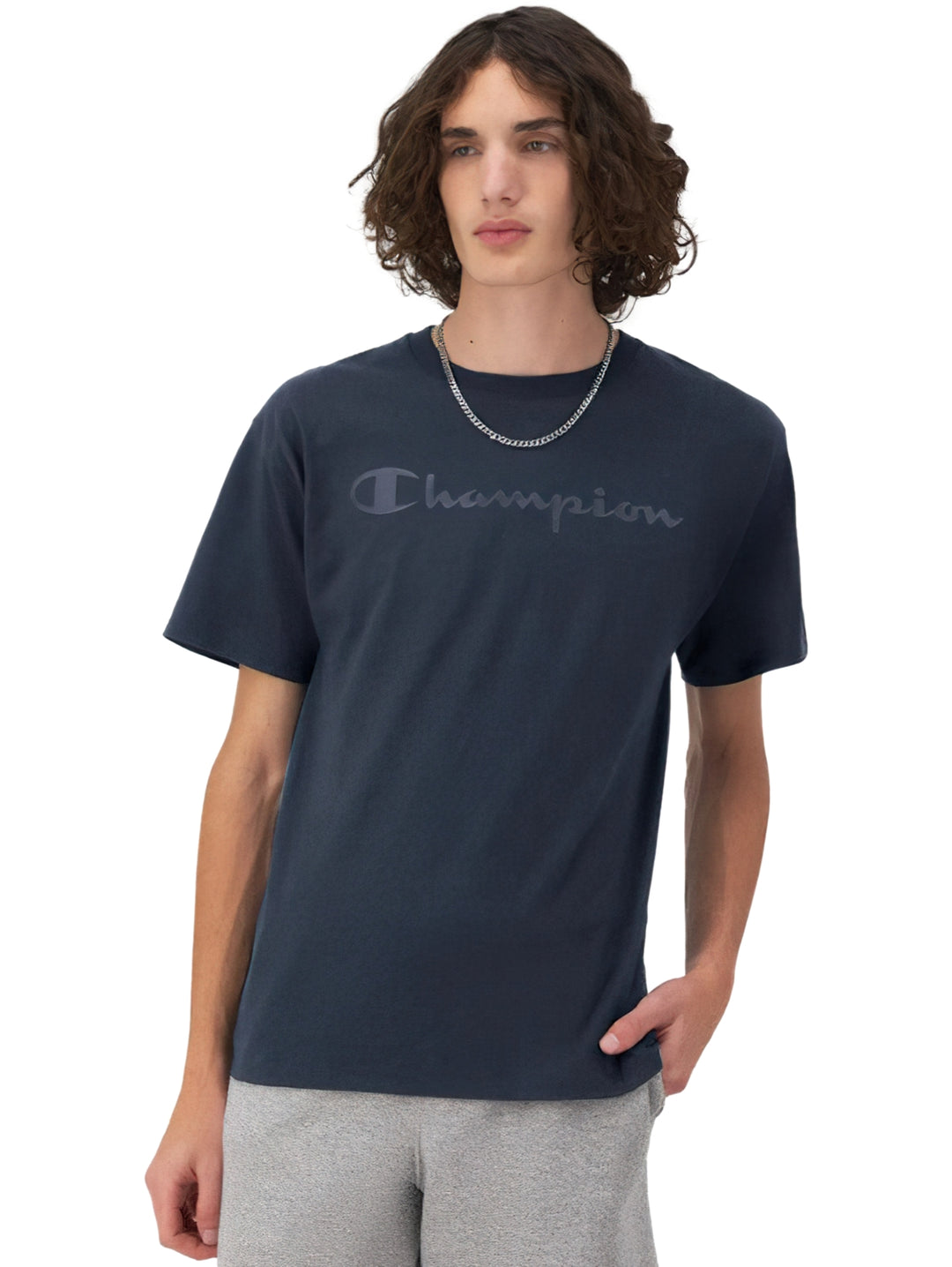 Hombre vistiendo una camiseta de manga corta color azul marino de la marca Champion con logotipo en el pecho.