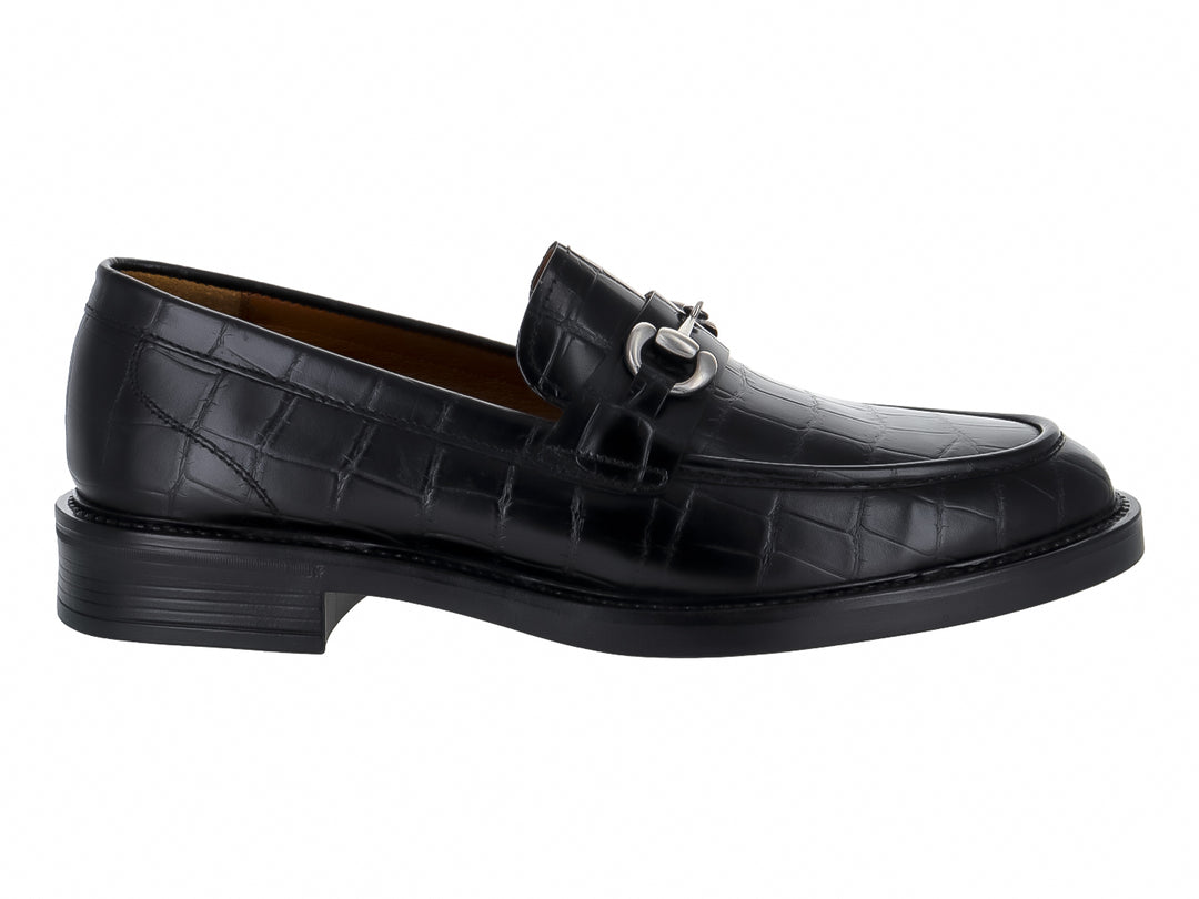 Zapato mocasín negro con textura de piel de lagarto y hebilla metálica plateada.