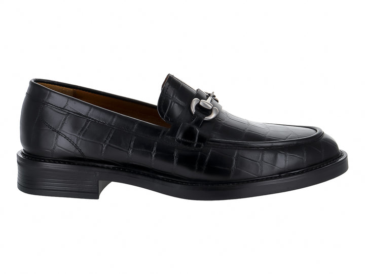 Zapato mocasín negro con textura de piel de lagarto y hebilla metálica plateada.