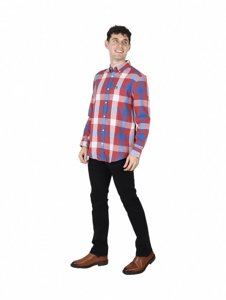 Hombre vistiendo una camisa de manga larga con estampado de cuadros en colores rojo, azul y blanco.