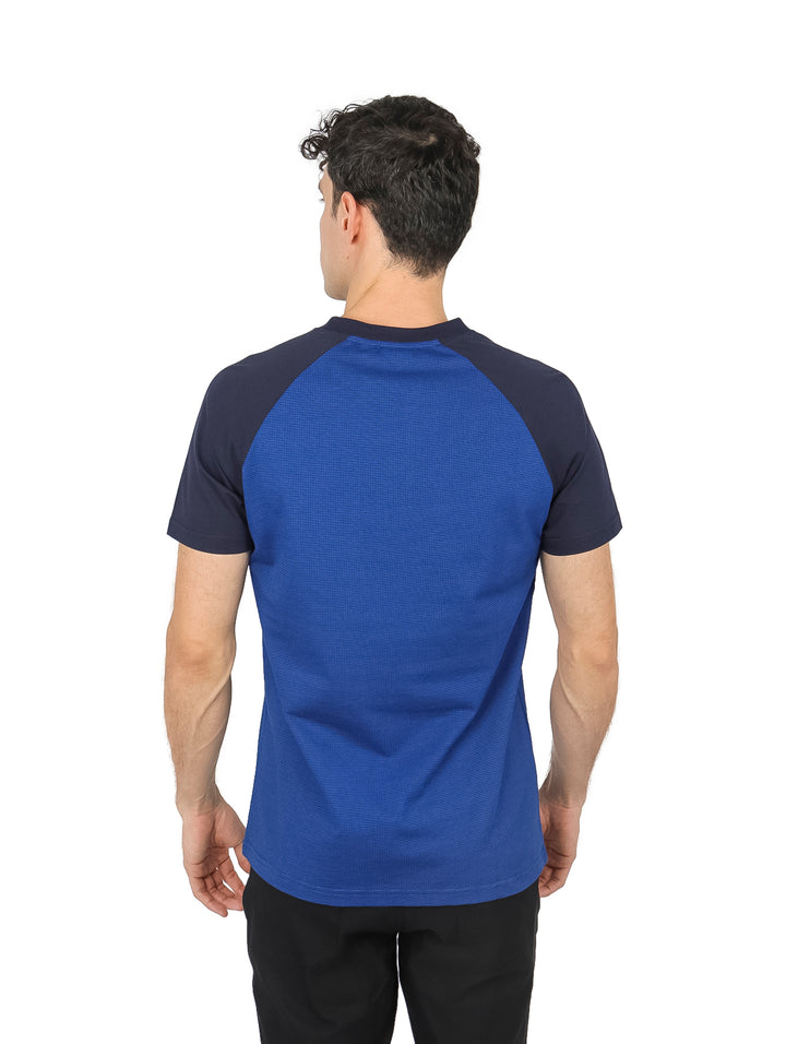 Hombre vistiendo playera Perry Ellis azul con mangas en contraste azul marino y cuello estilo Henley.