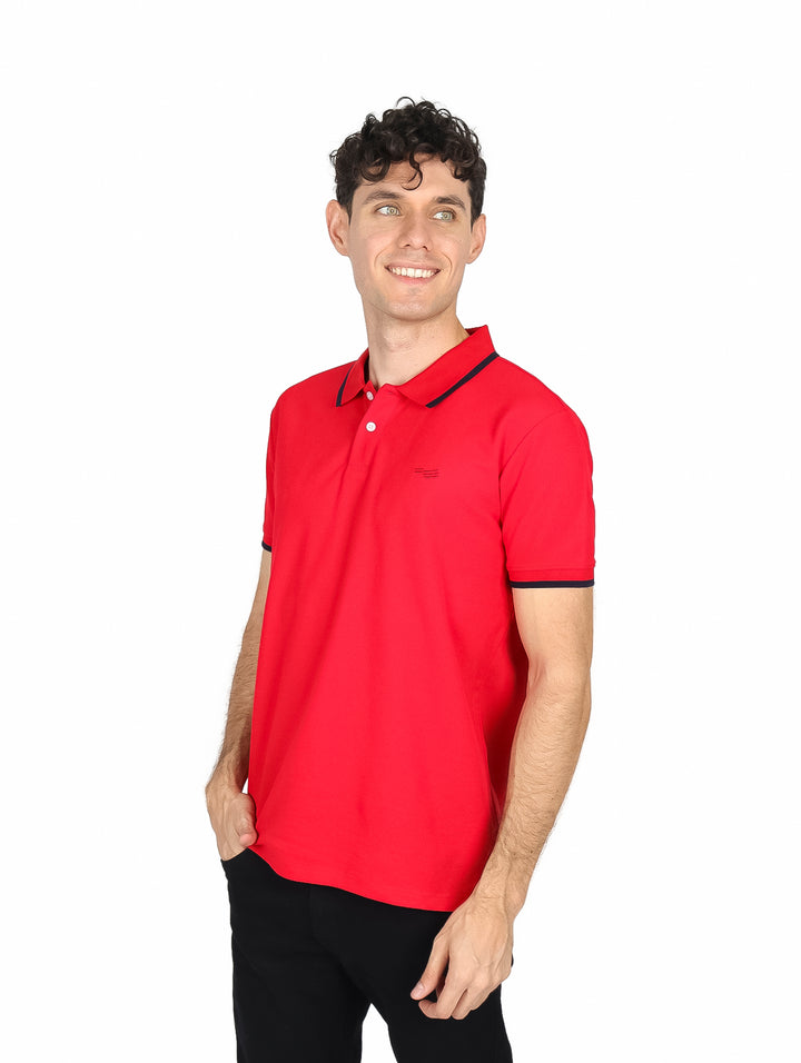 Hombre vistiendo una camiseta polo color rojo con detalles en azul marino en el cuello y mangas.