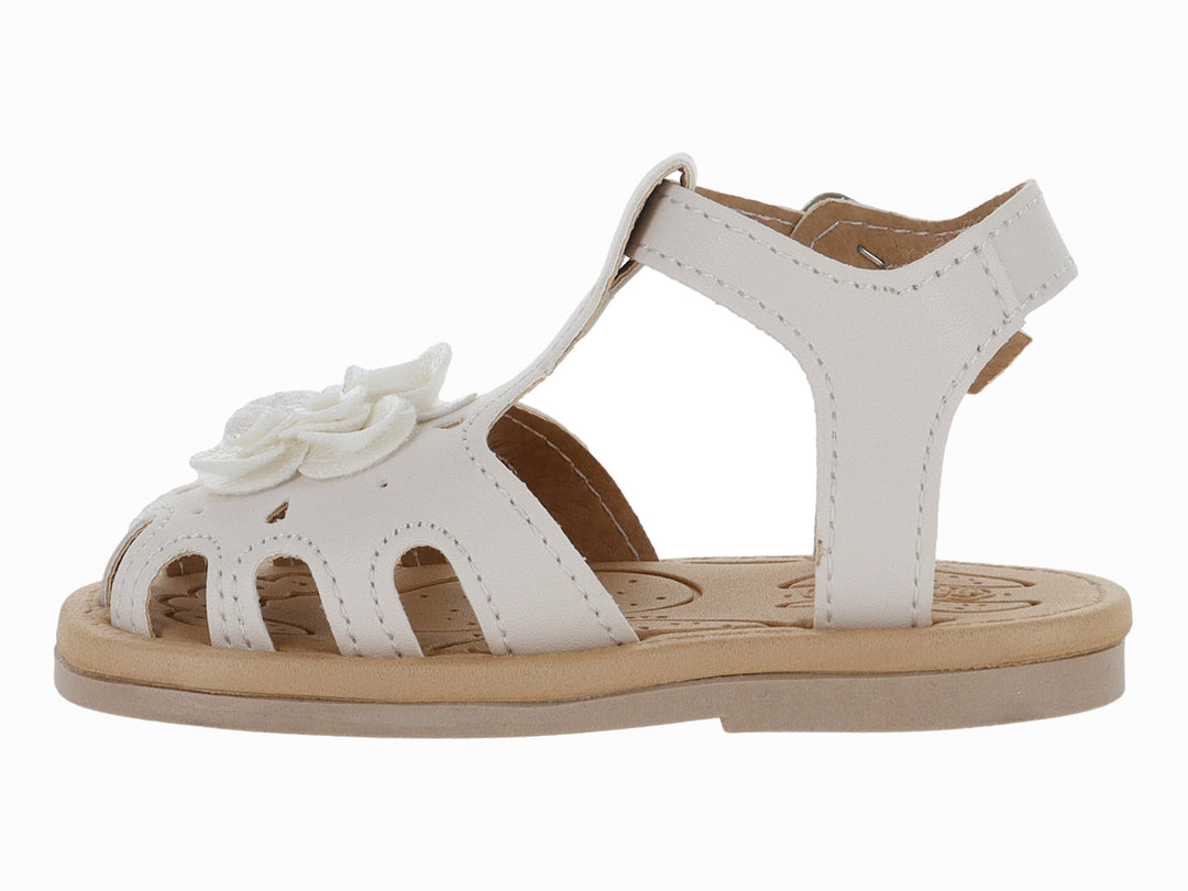 Sandalia blanca para niña con adorno de flor y hebilla metálica sobre suela beige.