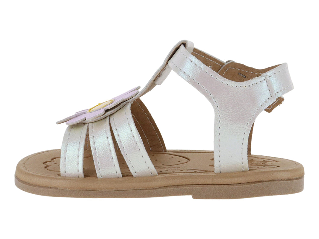 Sandalia blanca iridiscente para niña con adorno de flor rosa y suela beige.