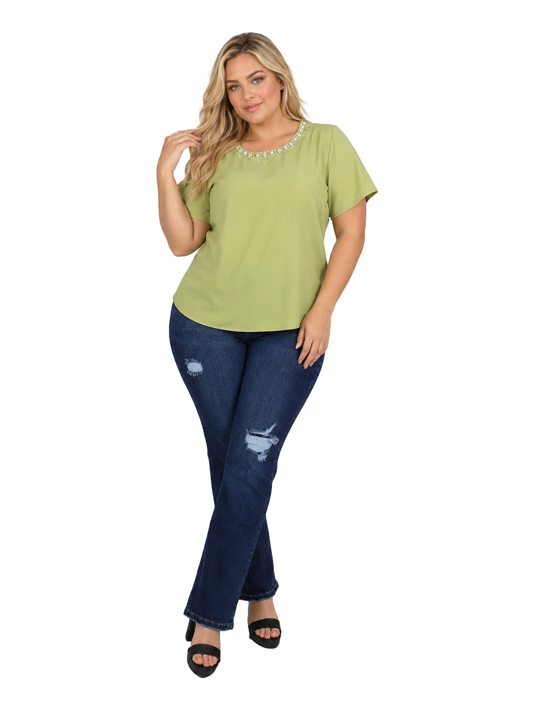 Mujer vistiendo blusa verde de manga corta con detalles de perlas en el cuello y jeans azules.