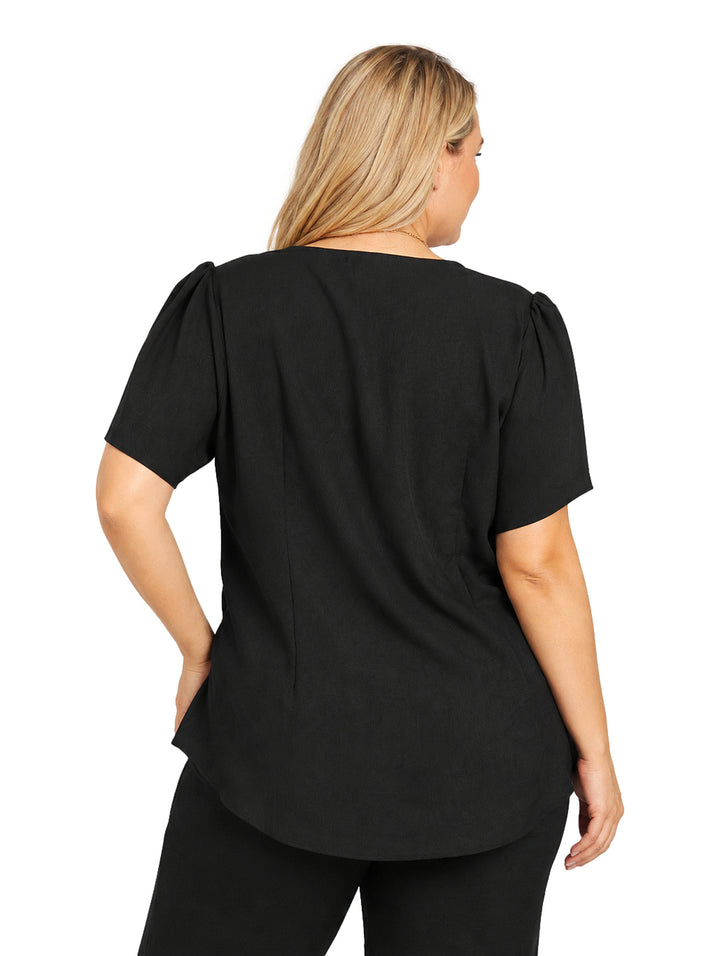 Mujer vistiendo blusa negra de manga corta y cuello redondo con un collar dorado largo decorativo.