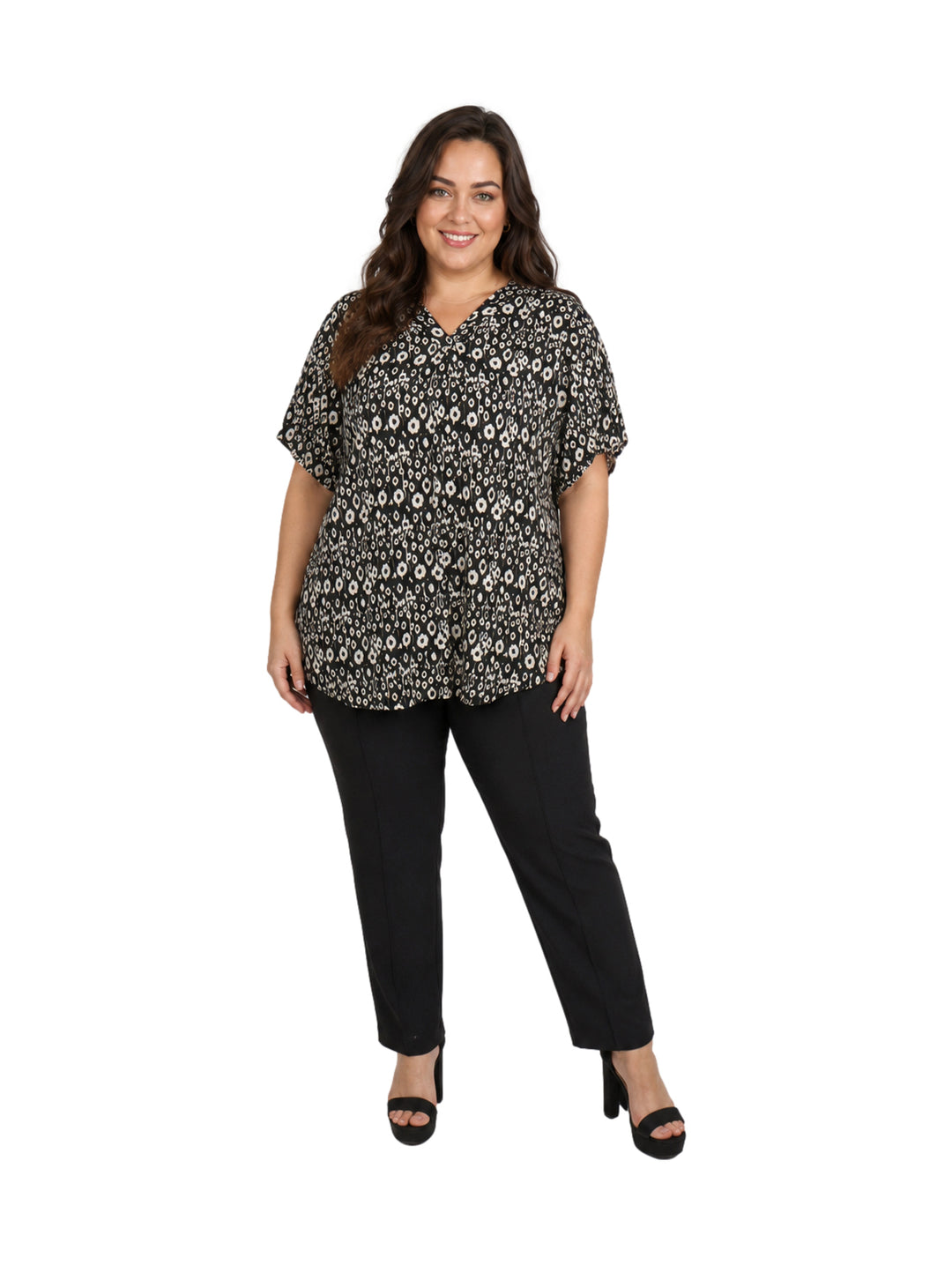 Mujer vistiendo blusa negra con estampado de flores blancas, cuello en V y manga corta.