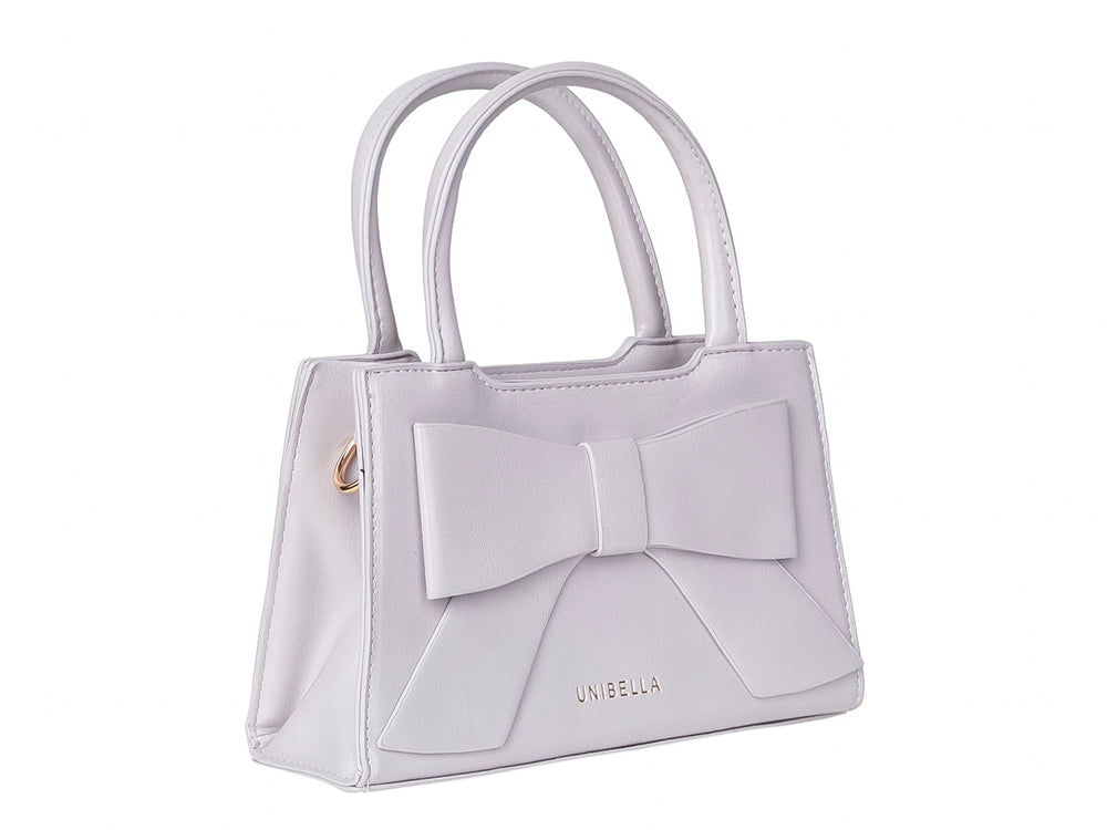 Bolso de mano color morado claro con un moño decorativo grande en la parte frontal y asas cortas.