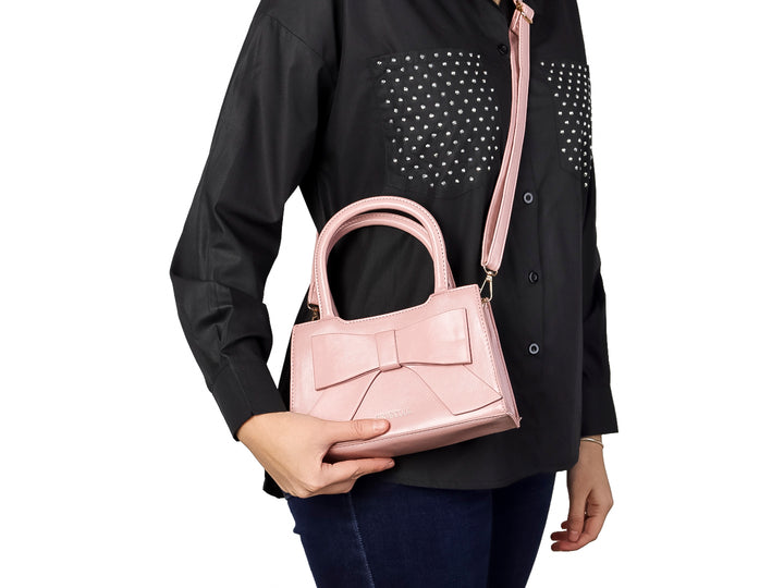 Bolso de mano color rosa con un moño decorativo grande en la parte frontal y asa corta.