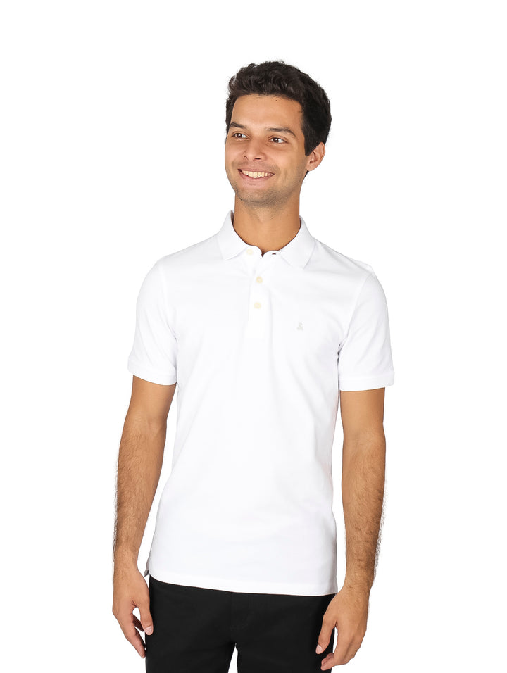 Hombre vistiendo una polo blanca de manga corta y pantalones negros sobre fondo blanco.