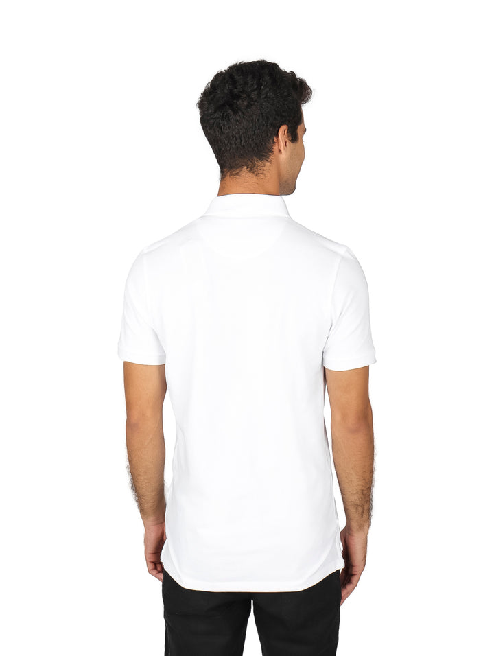 Hombre vistiendo una polo blanca de manga corta y pantalones negros sobre fondo blanco.