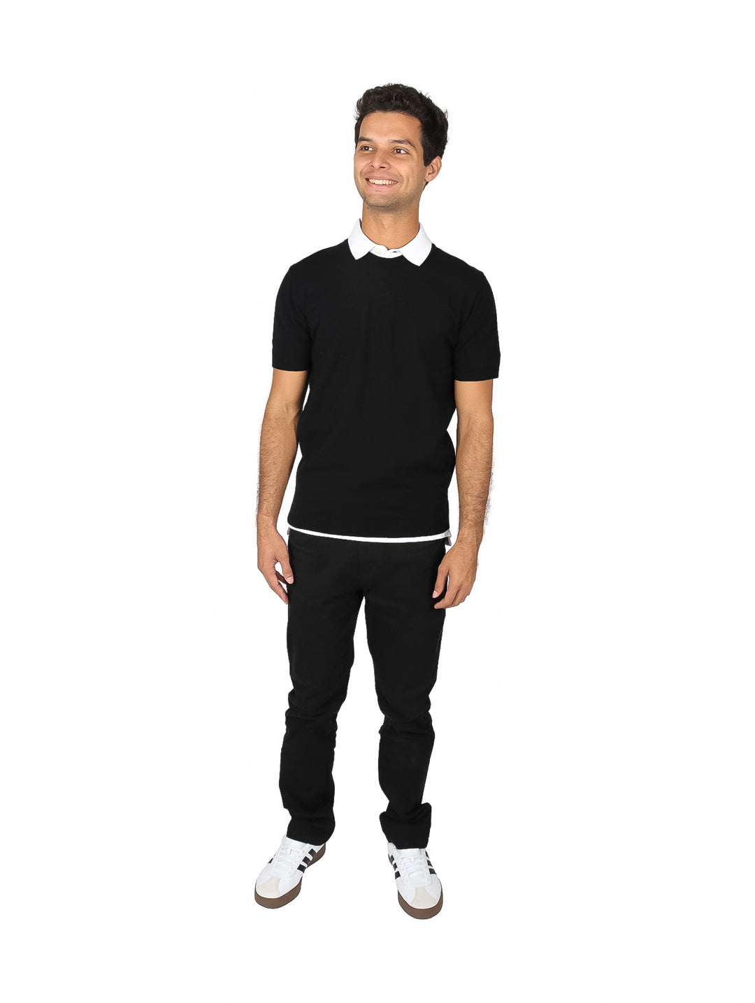Hombre vistiendo una polo blanca de manga corta y pantalones negros sobre fondo blanco.