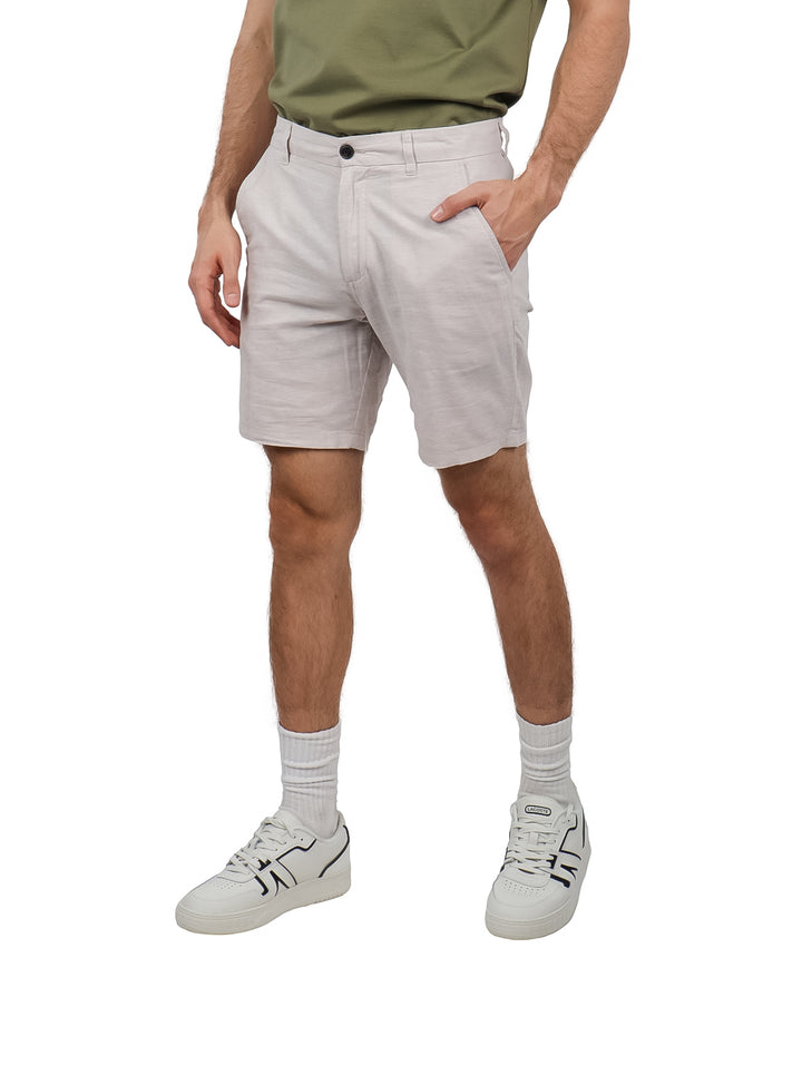 Hombre usando pantalones cortos de lino en color gris claro, estilo casual.