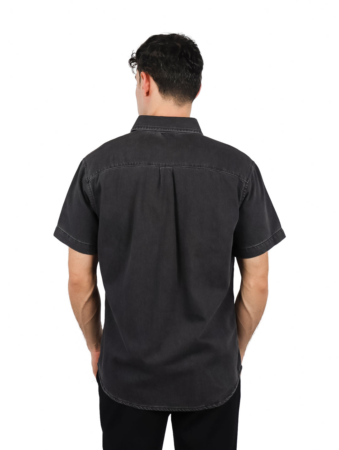 Hombre vistiendo una camisa de mezclilla color negro con manga corta y un bolsillo frontal.