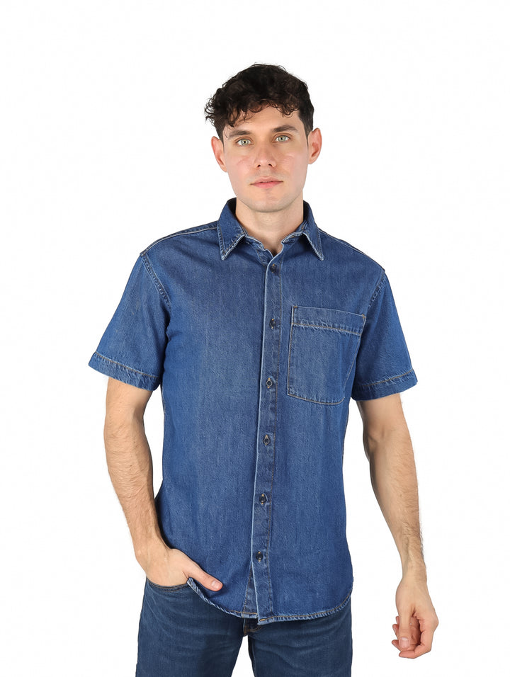 Hombre vistiendo una camisa de mezclilla azul de manga corta con un bolsillo frontal.