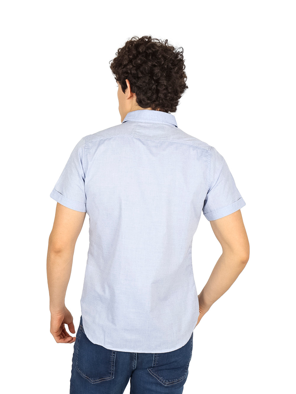 Hombre vistiendo una camisa de manga corta color azul cielo y pantalones vaqueros.