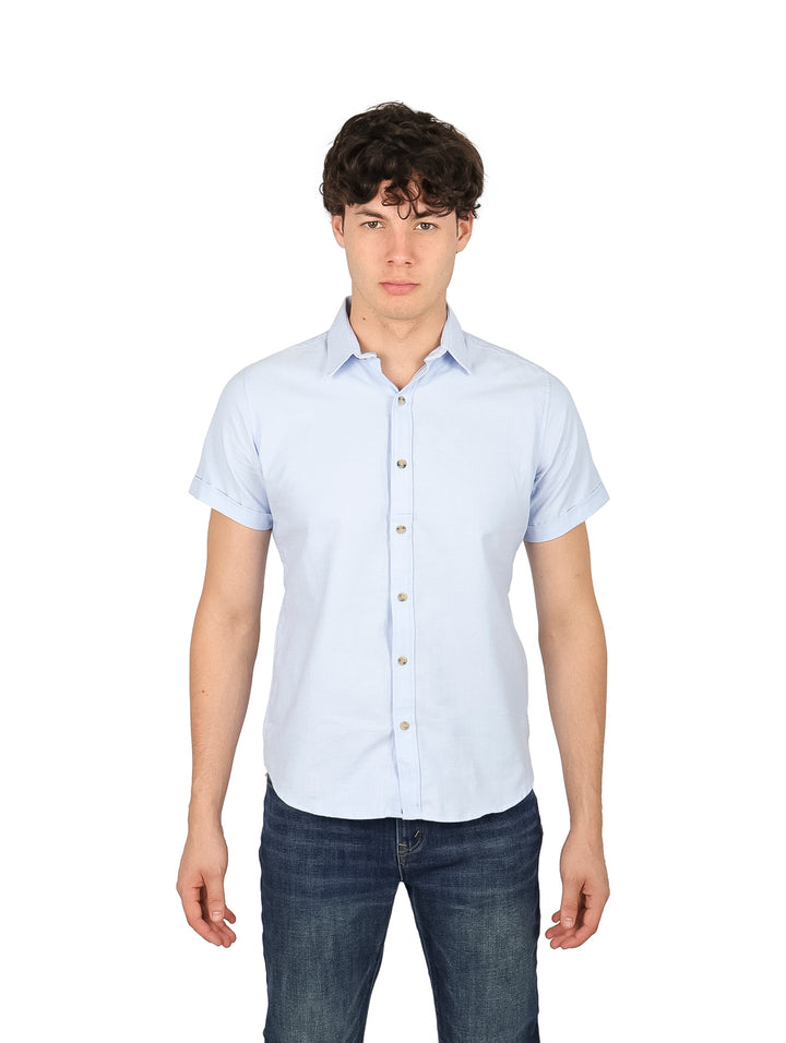 Hombre vistiendo una camisa casual de color azul claro con manga corta y botones frontales.