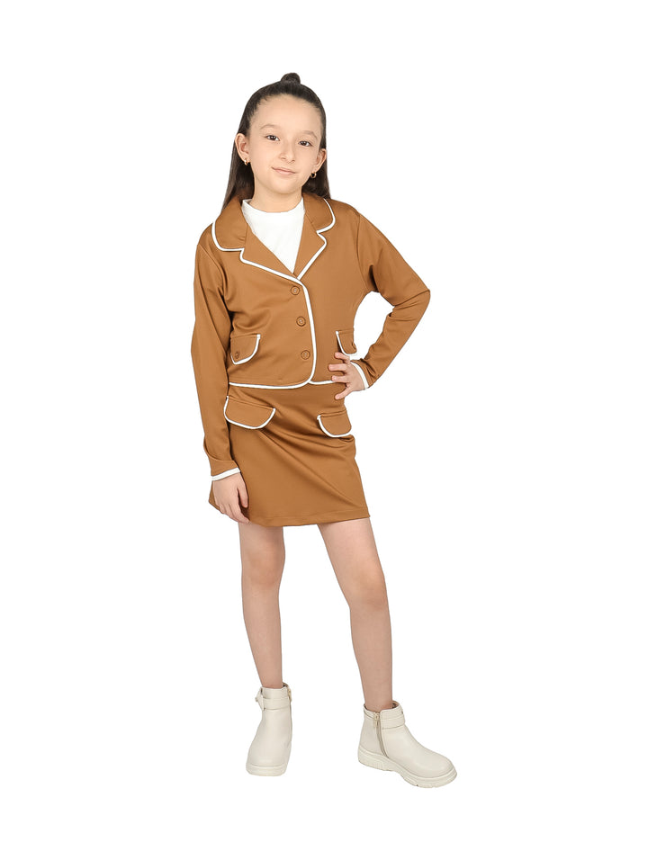 Niña con conjunto de chaqueta y falda color moka con ribetes blancos y botas blancas.